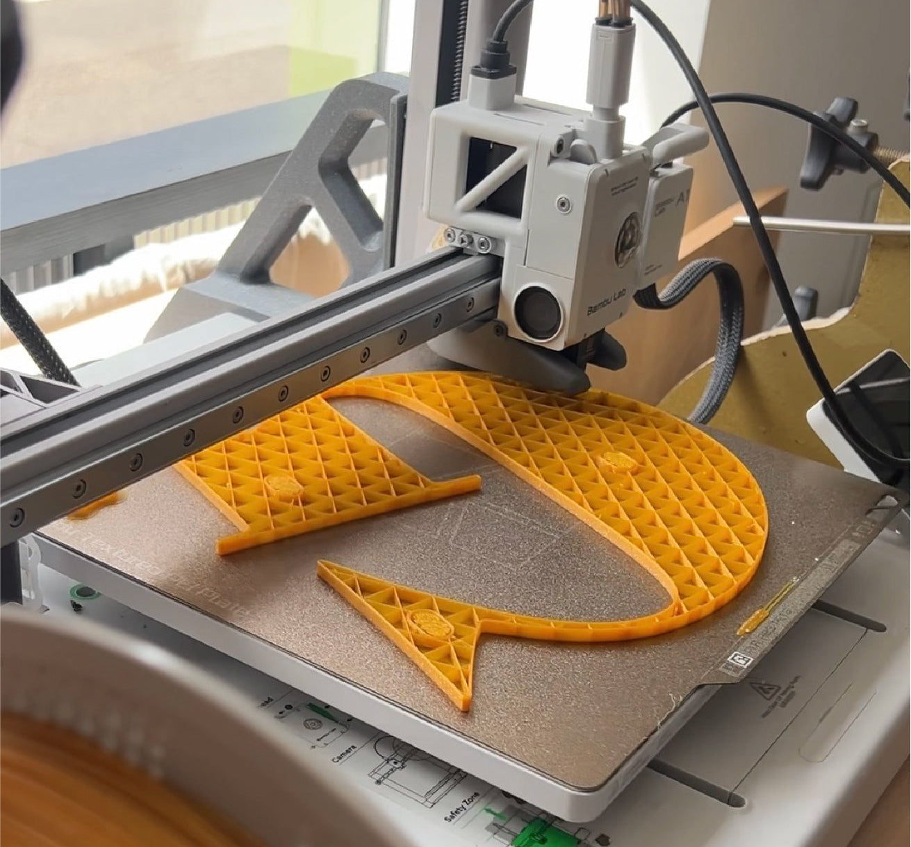 3D printer in operation with a yellow object on the print bed